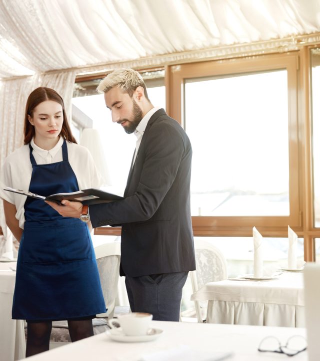 Director of a restaurant is giving work instructions to waitress Handsome young director of a restaurant is giving work instructions to waitresses
